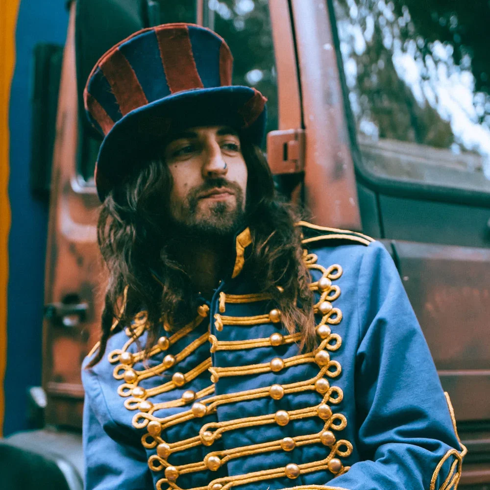Cam Cole, British one-man band, in a striped top hat by his van