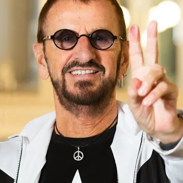 Ringo Starr smiling and showing a peace sign